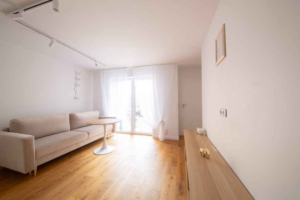 Nowa Przestrzeń – wnętrze mieszkania przy ulicy Pleszowskiej w Krakowie, salon z balkonem i jasną aranżacją